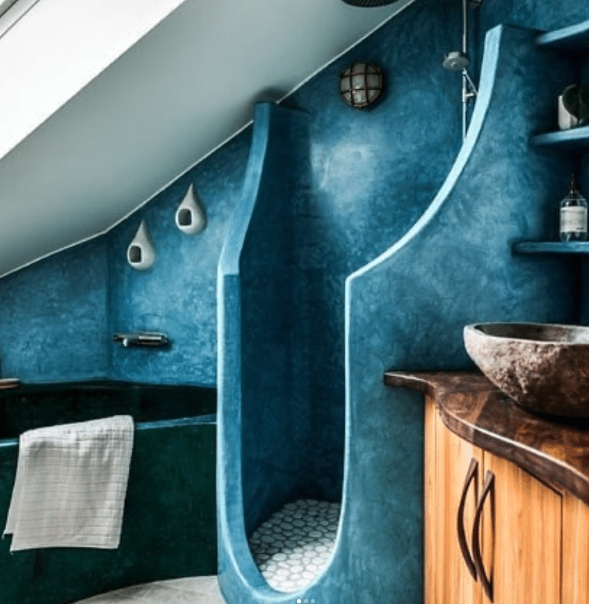 Blå tadelakt i badrum med välvda former, dusch och specialformat badkar.